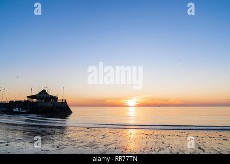 Sunrise, sunup, oltre il mare della Manica, a Viking Bay e il porto, Broadstairs. Sottile fascia di cloud e il cielo arancione sull'orizzonte con il cielo azzurro sopra. Foto Stock