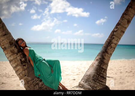 Donna in sotto una palma godendo la spiaggia Caraibica Foto Stock