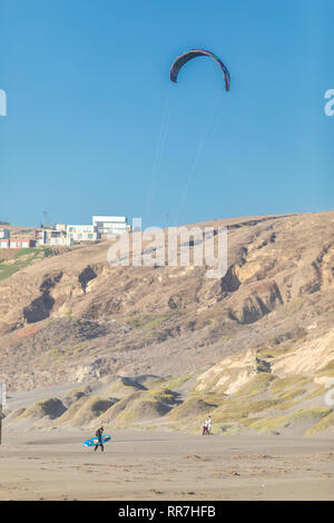 Kite surfer di camminare sulla spiaggia dopo la pratica kite surfing sull'Oceano Pacifico. Las Brisas spiaggia vicino a Santiago de Cile Foto Stock