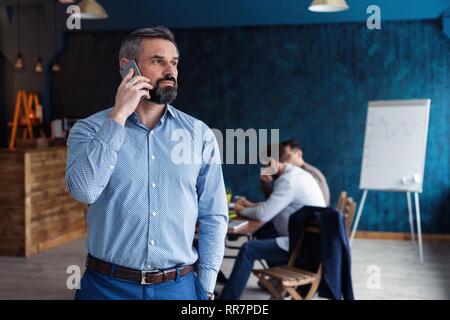 Bella coppia imprenditore sta parlando al telefono cellulare mentre si lavora in ufficio. Foto Stock