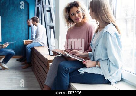 Femmina Creative Designer che lavorano in team. Due imprenditrici avente una riunione informale in un ufficio moderno. Foto Stock