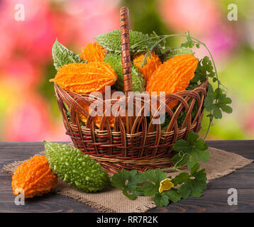 Il melone amaro o momordica in un cesto di vimini sul tavolo di legno con sfondo sfocato Foto Stock