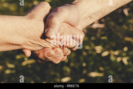 Close-up di immagine stringono le mani tra anziani donna e uomo. Il concetto di accordo. Foto Stock