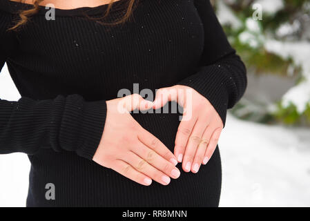 Dettaglio di un irriconoscibile della donna incinta, pancia in inverno. Foto Stock