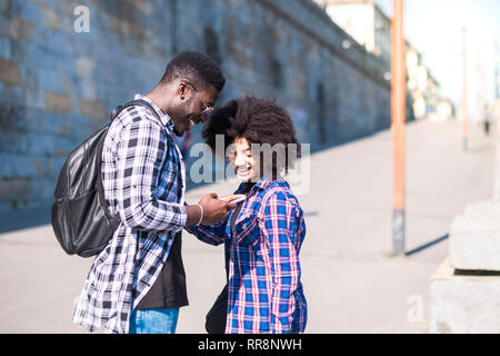 Paio di persone un uomo e una donna giovane ridendo alla ricerca di un telefono insieme - coppia felice nella città enjoyig il tempo libero attività outdoor - prima data lo Foto Stock