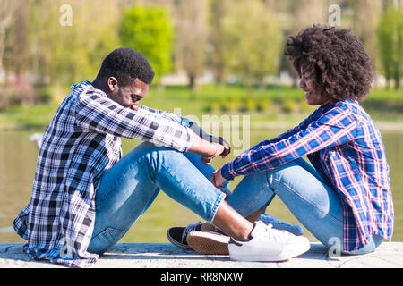 Nero Ragazza e ragazzo godere e divertirsi insieme all'esterno le attività per il tempo libero nei pressi di un parco - millenaria giovani in amicizia - casual hipster vestire Foto Stock