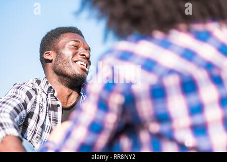 Black afro giovane ridere un sacco outdoor - bel ragazzo di ridere e divertirsi con la fidanzata visto dalla parte posteriore - gioiosi e felici le persone - maschio con Foto Stock