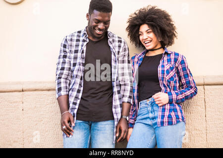 Felice africano nero razza mista giovane ridendo e godendo il rapporto e l'amicizia insieme con la parete in background - tempo libero atto Foto Stock