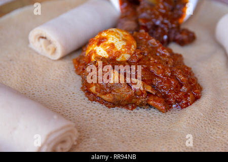 Ristoranti africani. Pollo e uovo Doro Wat con Injera - una pasta madre flatbread realizzato da teff farina. È il cibo nazionale dell'Etiopia, Eritrea, Somalia Foto Stock