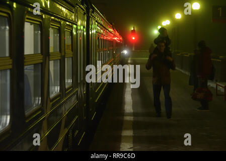 Dubna, Russia - 5 Novembre, 2018: treni pendolari e passeggeri a Dubna stazione ferroviaria nella fitta nebbia di notte. Foto Stock