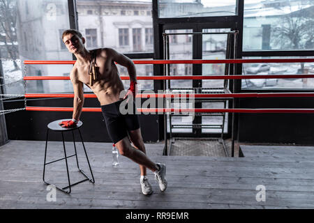 Atleta muscolare uomo con corda vicino a presiedere nell'anello Foto Stock