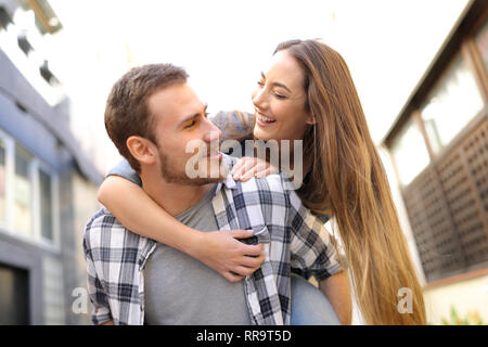 Felice coppia o amici stanno scherzando piggybacking in strada Foto Stock