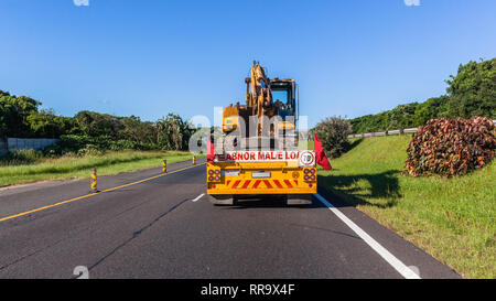 Escavatore terrapieno industriale macchina livellatrice su heavy duty carrello dello scanner a superficie piana è stato trasportato sull autostrada a closeup posteriore campagna fotografica blue sky giorno. Foto Stock