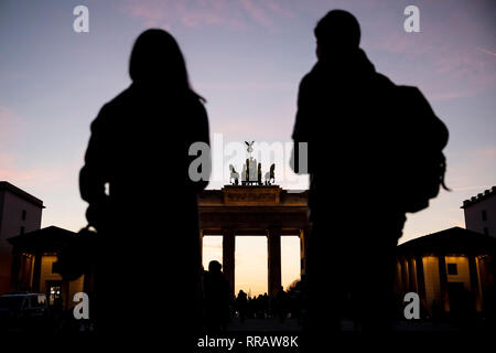 Berlino, Germania. Il 25 febbraio, 2019. Due passanti sono in piedi di fronte alla Porta di Brandeburgo con la Quadriga al crepuscolo. Credito: Christoph Soeder/dpa/Alamy Live News Foto Stock