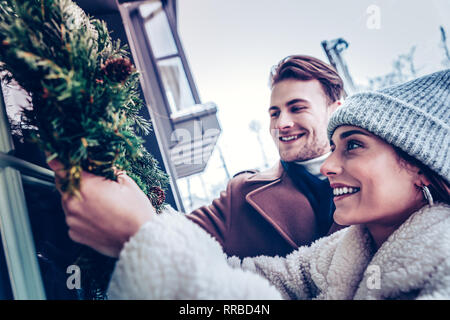 Ragazzo barbuto aiutando la sua donna attraente decorazione di casa Foto Stock