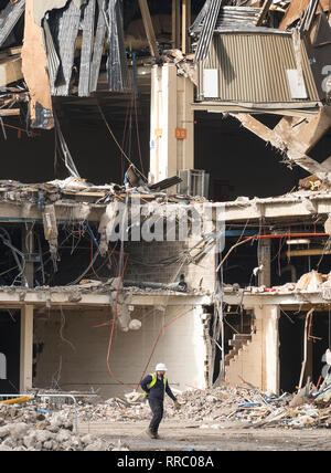 Operaio edile a piedi nella parte anteriore di una grande fabbrica demolito Foto Stock