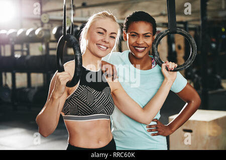 Due diversi giovani amici di sesso femminile in sportswear in piedi insieme da anelli in una palestra dopo un allenamento Foto Stock