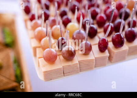 Spuntini leggeri in una piastra su un tavolo da buffet. Mini assortiti tartine, delizie e snack, ristorante cibo a caso. Uva rossa, formaggio e prosciutto. Foto Stock