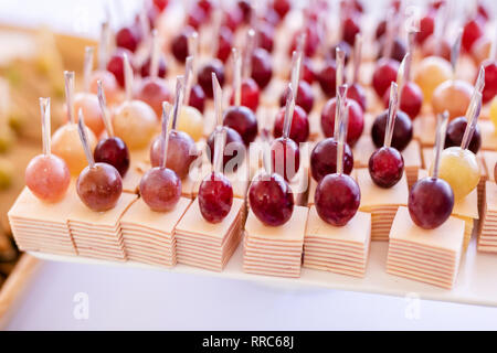 Spuntini leggeri in una piastra su un tavolo da buffet. Mini assortiti tartine, delizie e snack, ristorante cibo a caso. Uva rossa, formaggio e prosciutto. Foto Stock