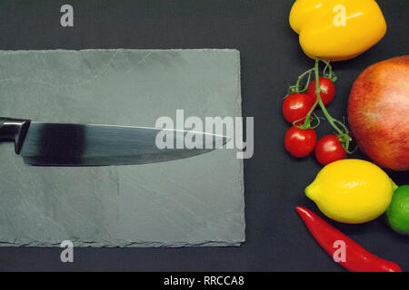 L'ardesia tagliere con coltello lungo il lato di frutta e verdura assortimento Foto Stock