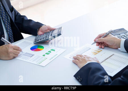 Due imprenditori sono profondamente rivedendo un report finanziari per un ritorno sugli investimenti o rischio di investimento analisi su una scrivania bianca. Copia superiore spazio incl Foto Stock