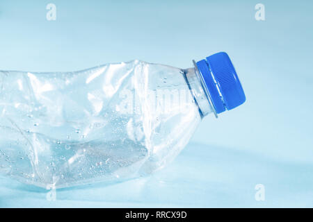 Rifiuti di plastica concetto: scartato sgualciti di acqua in bottiglia in sfondo blu, vista dettagliata. Vista ravvicinata di una gettata uso singola bottiglia di plastica DIP Foto Stock