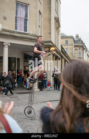 Un animatore di strada in stallo bagno st. Fire juggling su un ciclo di mono, naturalmente.. Foto Stock