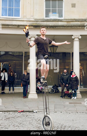 Un animatore di strada in stallo bagno st. Fire juggling su un ciclo di mono, naturalmente.. Foto Stock