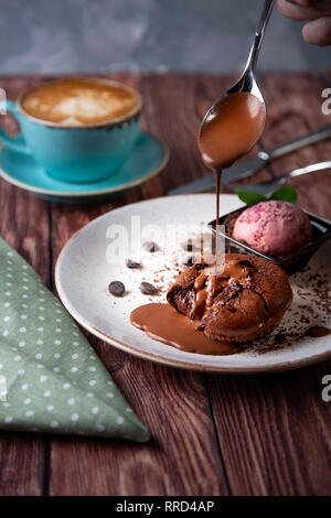 Cioccolato torta di lava fusa con gelato sulla piastra e cappuccino. Palline di gelato in coppa . Nero scuro dello sfondo. Foto Stock