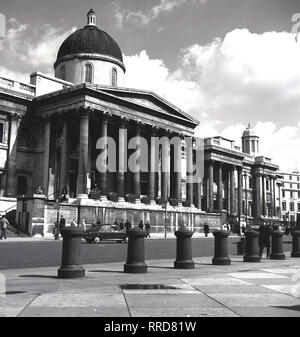 Anni sessanta, storico vista frontale di ingresso colonnato alla National Gallery, a Trafalgar Square a Londra, Inghilterra, Regno Unito. Fondata nel 1824, il museo di arte contiene una delle più grandi collezioni di dipinti al mondo. Foto Stock