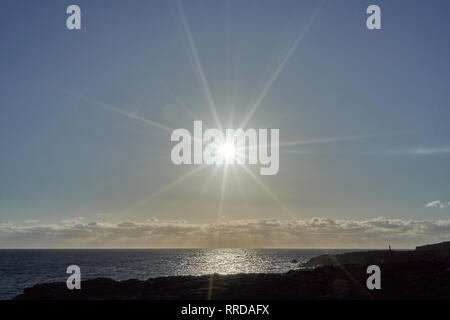 Vista di Bright sole che splende sopra il mare e la costa rocciosa Foto Stock