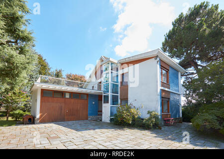 Anni Settanta villa con giardino in una soleggiata giornata estiva, cielo blu chiaro Foto Stock