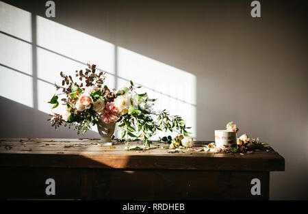 Il piatto con una gustosa torta decorata bloom bud sul tavolo di legno con mazzo di crisantemi, rose e rametti di piante in vaso tra foglie secche in backgr grigio Foto Stock