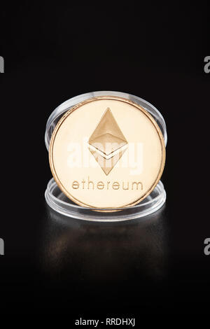 Ethereum medaglia d'oro in moneta trasparente contenitore su sfondo nero, tracciato di ritaglio Foto Stock