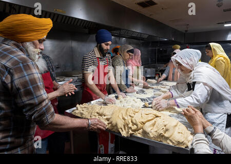 Donne e uomini volontari per un langar, un tempio sikh cucina, preparare roti, una rotonda pane sottile. In South Richmond Hill, Queens, a New York City. Foto Stock