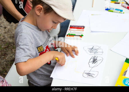 Bambino kid disegno multicolore con le matite colorate su carta bianca all'aperto Foto Stock