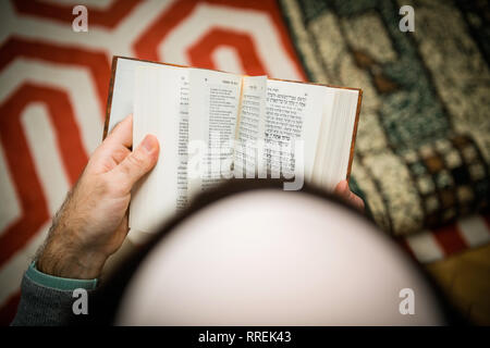 Libro di lettura vista da sopra del maschio ebreo indossando kippa , lettura orante bi-lingue ebraico mahzor francese libro di preghiera da 1920 utilizzato in alto i Giorni santi di Rosh Hashanah e Yom Kippur. Foto Stock