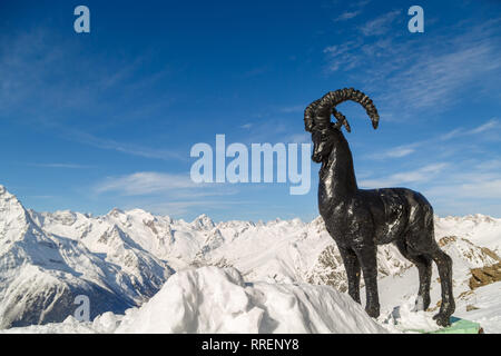 DOMBAI, RUSSIA, febbraio 27, 2018: monumento alle capre di montagna sullo sfondo delle cime più alte dei monti del Caucaso Foto Stock