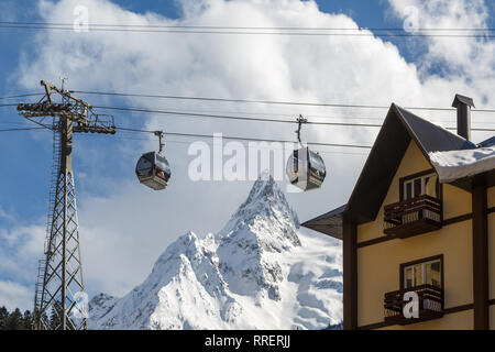 DOMBAY, RUSSIA, febbraio 28, 2018: cabine di ski lift contro le alte cime innevate montagne del Caucaso Foto Stock