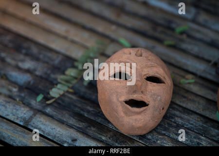 Maschera in terracotta su sfondi di bambù. Foto Stock
