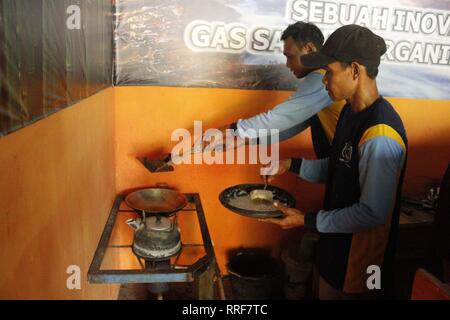 Madiun, Indonesia. Il 21 febbraio, 2019. Lavoratori rfi tempeh e cuocere l'acqua a bollire per preparare il caffè puro in polvere nella discarica Winongo area, Madiun città. Essi utilizzano i rifiuti organici come gas combustibile. Credito: Ajun alleato/Pacific Press/Alamy Live News Foto Stock