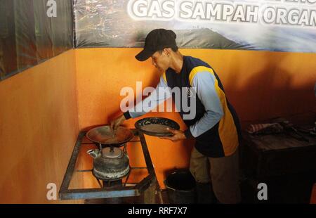 Madiun, Indonesia. Il 21 febbraio, 2019. Lavoratori rfi tempeh e cuocere l'acqua a bollire per preparare il caffè puro in polvere nella discarica Winongo area, Madiun città. Essi utilizzano i rifiuti organici come gas combustibile. Credito: Ajun alleato/Pacific Press/Alamy Live News Foto Stock