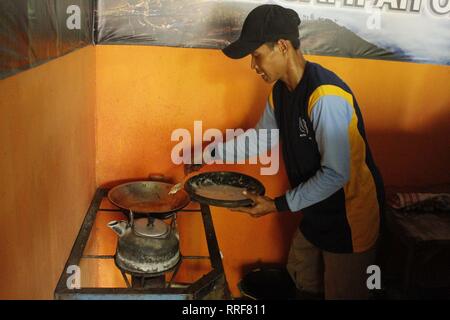 Madiun, Indonesia. Il 21 febbraio, 2019. Lavoratori rfi tempeh e cuocere l'acqua a bollire per preparare il caffè puro in polvere nella discarica Winongo area, Madiun città. Essi utilizzano i rifiuti organici come gas combustibile. Credito: Ajun alleato/Pacific Press/Alamy Live News Foto Stock