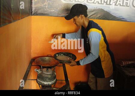 Madiun, Indonesia. Il 21 febbraio, 2019. Lavoratori rfi tempeh e cuocere l'acqua a bollire per preparare il caffè puro in polvere nella discarica Winongo area, Madiun città. Essi utilizzano i rifiuti organici come gas combustibile. Credito: Ajun alleato/Pacific Press/Alamy Live News Foto Stock