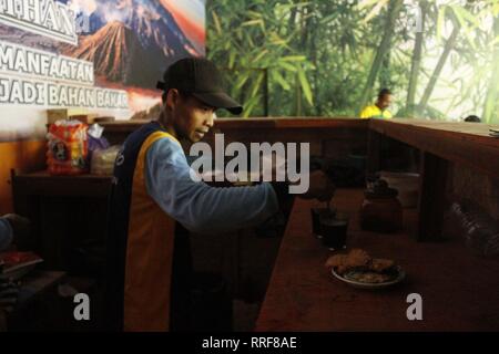 Madiun, Indonesia. Il 21 febbraio, 2019. Lavoratori rfi tempeh e cuocere l'acqua a bollire per preparare il caffè puro in polvere nella discarica Winongo area, Madiun città. Essi utilizzano i rifiuti organici come gas combustibile. Credito: Ajun alleato/Pacific Press/Alamy Live News Foto Stock