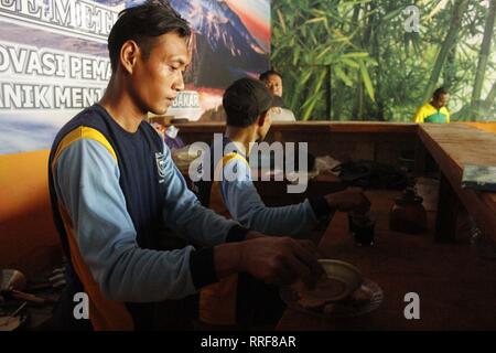 Madiun, Indonesia. Il 21 febbraio, 2019. Lavoratori rfi tempeh e cuocere l'acqua a bollire per preparare il caffè puro in polvere nella discarica Winongo area, Madiun città. Essi utilizzano i rifiuti organici come gas combustibile. Credito: Ajun alleato/Pacific Press/Alamy Live News Foto Stock