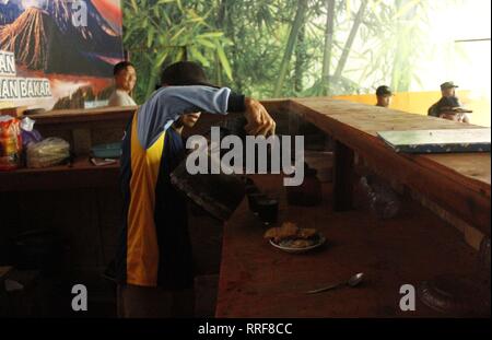 Madiun, Indonesia. Il 21 febbraio, 2019. Lavoratori rfi tempeh e cuocere l'acqua a bollire per preparare il caffè puro in polvere nella discarica Winongo area, Madiun città. Essi utilizzano i rifiuti organici come gas combustibile. Credito: Ajun alleato/Pacific Press/Alamy Live News Foto Stock