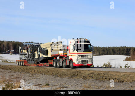 Salo, Finlandia - 22 Febbraio 2019: Volvo FH16 700 camion rimorchio con collo d'oca del Cale Janhunen Metso Lokotrack ST4.8 schermo mobile lungo la strada in inverno. Foto Stock