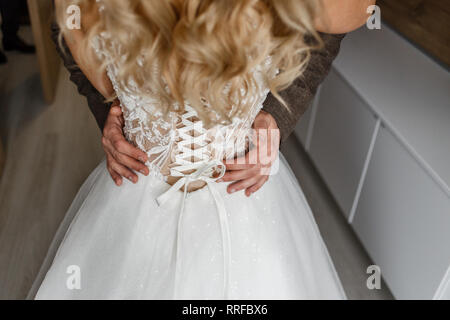 Sposi tenendo le mani e abbracciando in hotel. Foto Stock