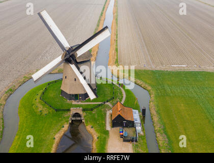 Tipico mulino a vento olandese del XVII secolo il colpo da sopra con un drone circondata da un canale nei campi dell'Olanda Foto Stock